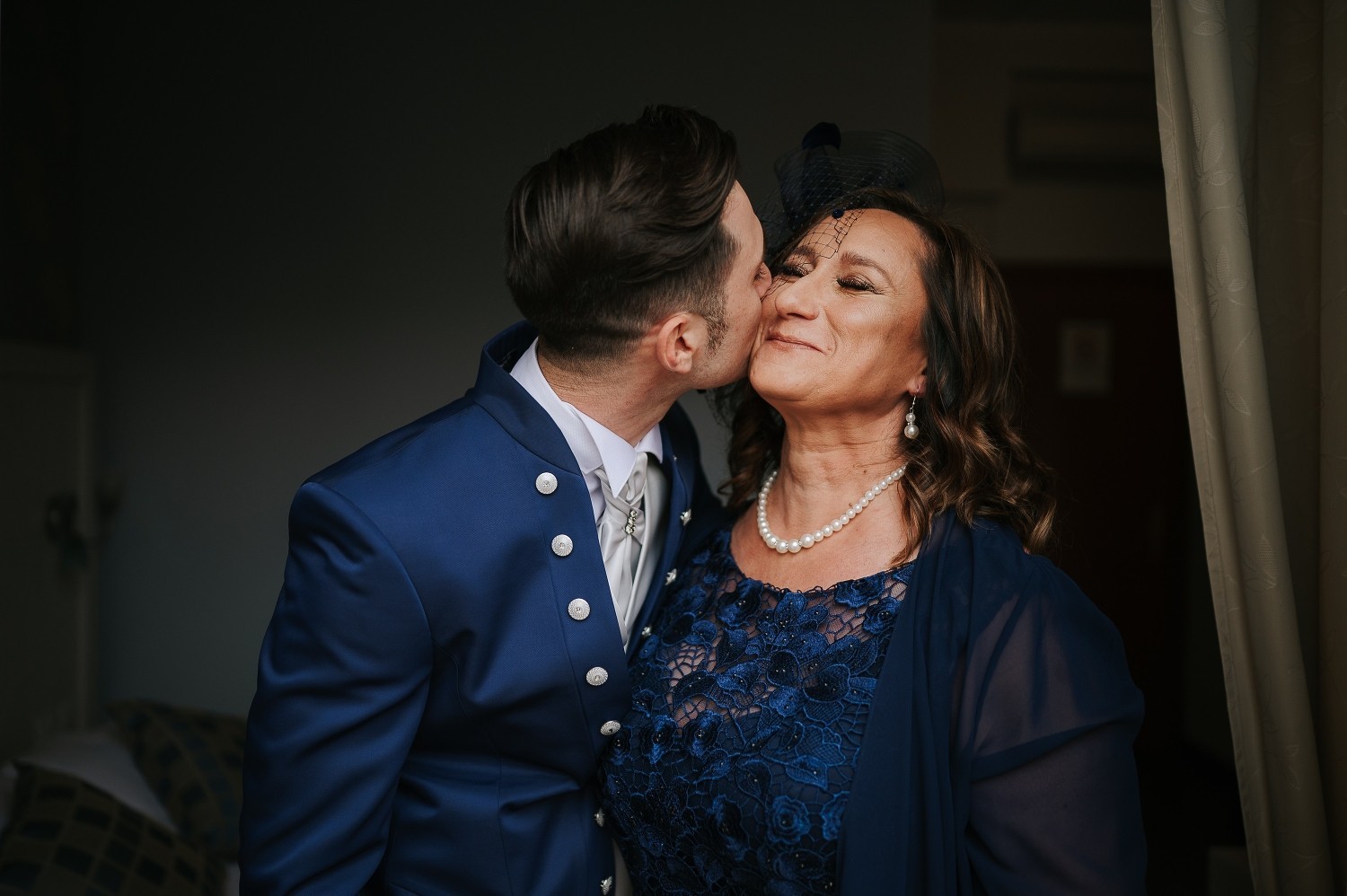 The groom kisses his mother on his wedding day 
